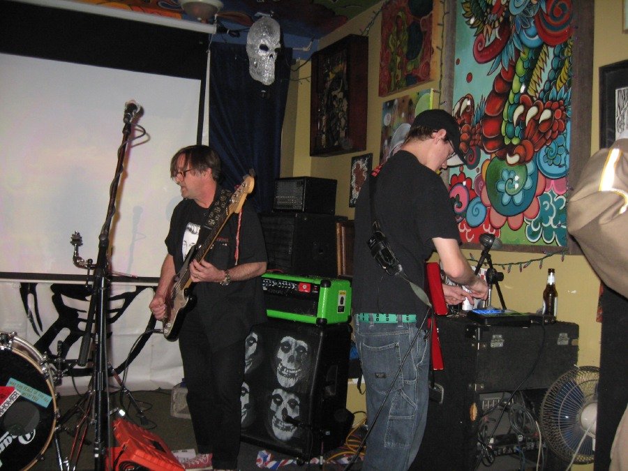 Live performance still — bass and electronics on a small indoor stage